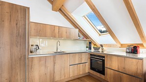 A modern kitchen with wooden cabinets, a built-in oven, and a skylight.