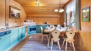 Un interior de madera con cocina, comedor y ventana con cortinas.