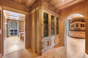 Ein Zimmer mit Holzwänden, einem großen Schrank, einem Bett und Blick durch einen Bogen.