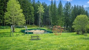 Un parque con un columpio, un arenero y una estructura de juego geométrica.