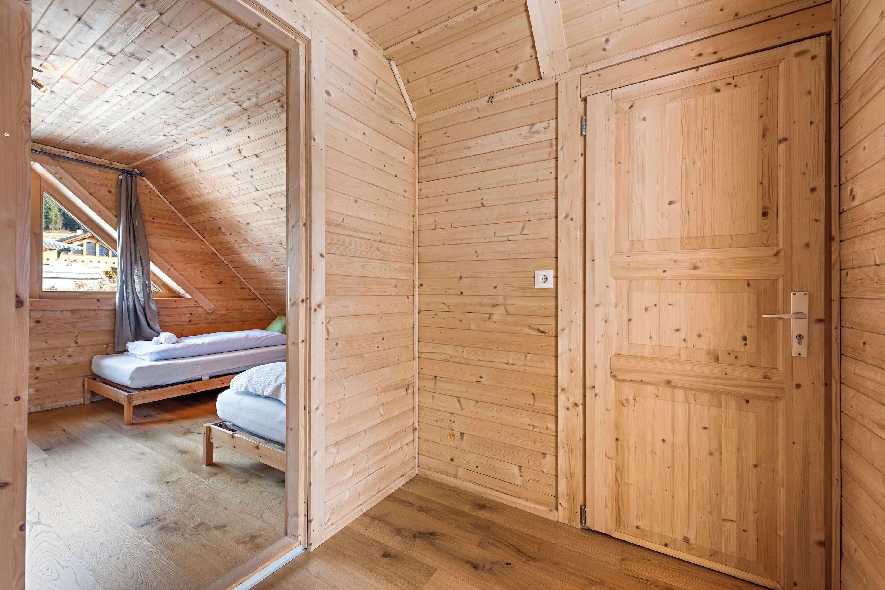 Un intérieur en bois avec un lit, une porte et une fenêtre.