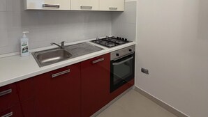 A kitchen with white cabinets, a stainless steel sink, a gas stove, and a built-in oven. - Guest House Colfiorito by Ospitaci-appartamento (Colfiorito)