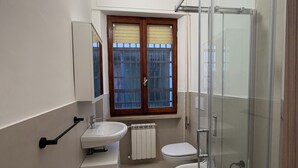 A modern bathroom with a glass shower enclosure, a double sink, and a toilet. - Guest House Colfiorito by Ospitaci-appartamento (Colfiorito)