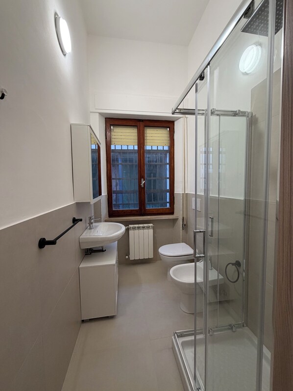 Un baño moderno con cabina de ducha de vidrio, lavamanos doble y un inodoro.
