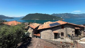 A coastal village with stone buildings, a clear blue sky, and a view of the sea and mountains. - La Casa della Nonna - Two Bedroom House, Sleeps 6 (Sale Marasino)
