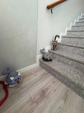 Un escalier avec une main courante en bois, un jouet en peluche sur le sol et un jouet rayé sur les marches.