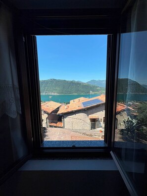 Une fenêtre donnant sur un paysage montagneux et un plan d’eau.