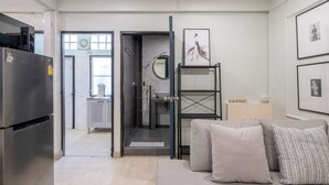 A modern kitchen with a refrigerator, a glass door leading to a bathroom, and a sofa with cushions. - Arun Sa Wad House Lad phrao 2 Guests (Bangkok)