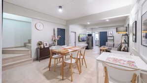 A modern living room with a dining area, a staircase, and a kitchen in the background. - Arun Sa Wad House Lad phrao 2 Guests (Bangkok)