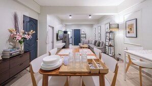 A modern dining area with a wooden table, white chairs, and a vase of flowers. - Arun Sa Wad House Lad phrao 2 Guests (Bangkok)