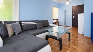 Un saló modern amb un sofà modular, una taula de centre de vidre i una zona de menjador al fons.
