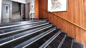 Una escala amb trams de marbre negre, barana de fusta i una obra d'art penjada a la paret.