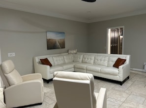 A living room with a sectional sofa, a recliner, and a painting on the wall.