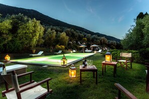 Ein Poolbereich mit Liegestühlen, einem Esstisch mit Gläsern und Flaschen sowie Laternen.