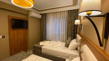 Habitación de hotel con dos camas, un televisor, un aire acondicionado y una lámpara.