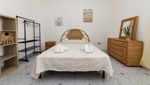 Ein Schlafzimmer mit einem Bett, einer Holzkommode, einem Spiegel, einem Regal und zwei Wandbildern.