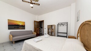 Ein Schlafzimmer mit einem Bett, einem Schlafsofa, einem Holzkasten und einem gerahmten Bild an der Wand.