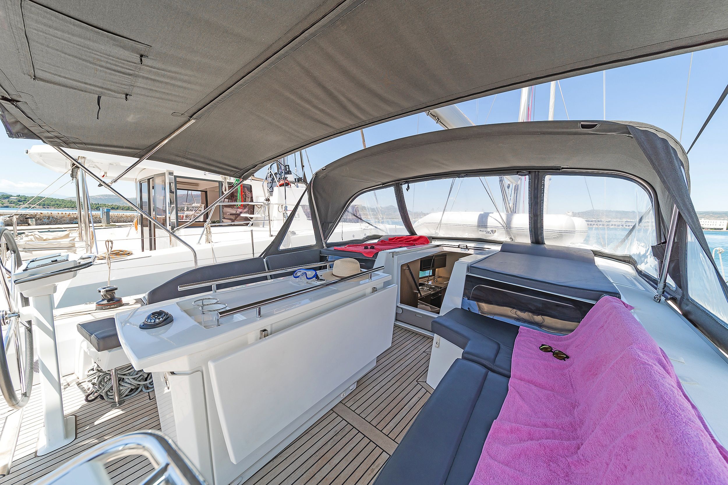 A boat's interior with a control panel, seating area, and a view of the marina.