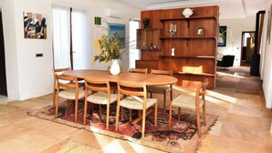 A dining area with a wooden table and chairs, a vase with flowers, and a wooden bookshelf. - Green Oasis 2 (Lacona)