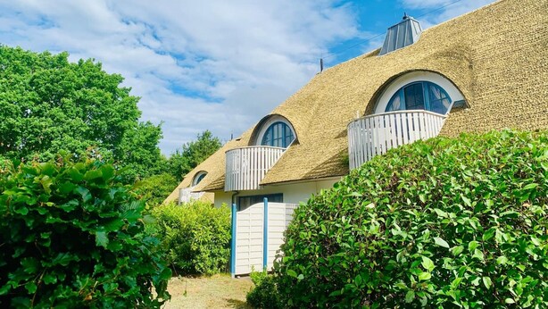A house with a thatched roof, a white door, and a small balcony. - Idyllic Thatched Apartment, Schwalbe Wieck Darß, 2 Bedrooms, 2 Balconies, Near Water (Wieck auf Darß)