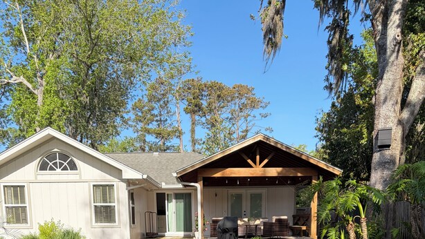 A patio with Adirondack chairs, a stone fire pit, and a covered outdoor seating area. - Spacious 4 Bed/3 Bath house with pool, fenced backyard, fire pit, covered porch. (St. Simons Island)