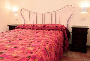 A bed with a patterned quilt, two bedside tables, and wall-mounted lights. - Romantic Holiday Villa Getaway in Umbria (Assisi)