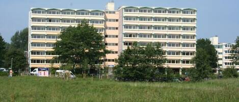 A multi-story building with a flat roof and a series of windows.