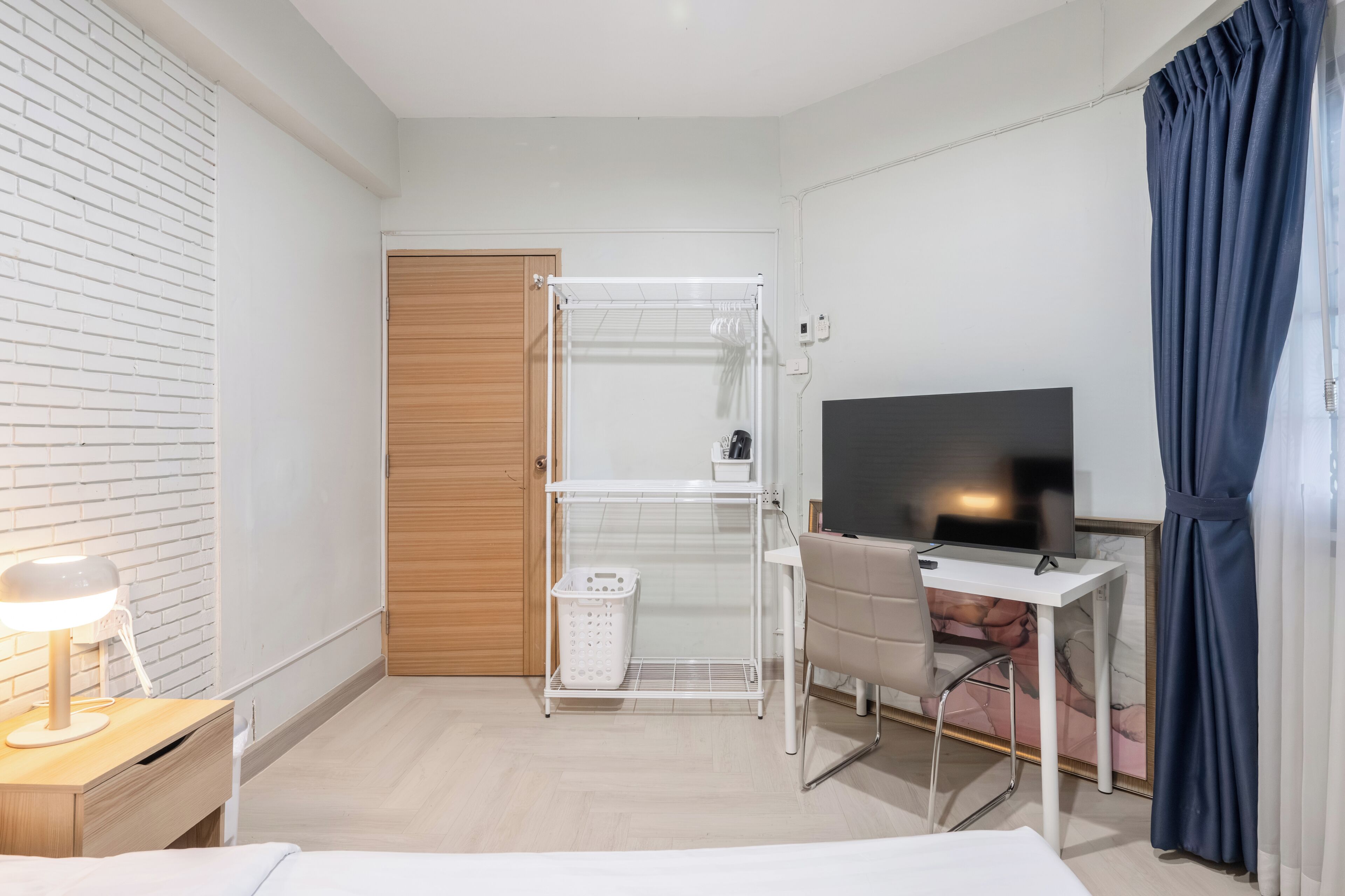 Une chambre d’hôtel comprenant un lit, un bureau avec une chaise, une télévision, une armoire et un panier à linge.
