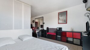 Une chambre à coucher avec un lit, une commode, un miroir et un tableau encadré accroché au mur.