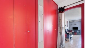 Un couloir avec des portes rouges, une porte blanche et un rideau à rayures.