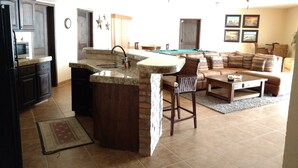 Een keuken met een bar, een pooltafel en een woonkamer met een bank en een salontafel.