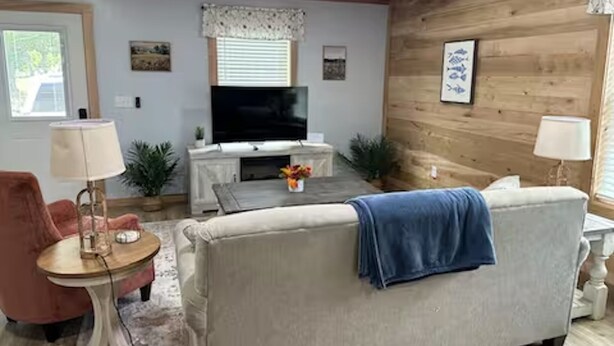 A living room with a sofa, armchair, television, and decorative items.