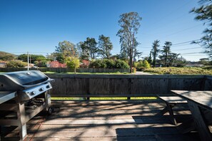 A barbecue grill, picnic table, and wooden fence in a backyard setting.