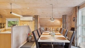 Comedor con mesa de madera, sillas de cuero y lámpara colgante.