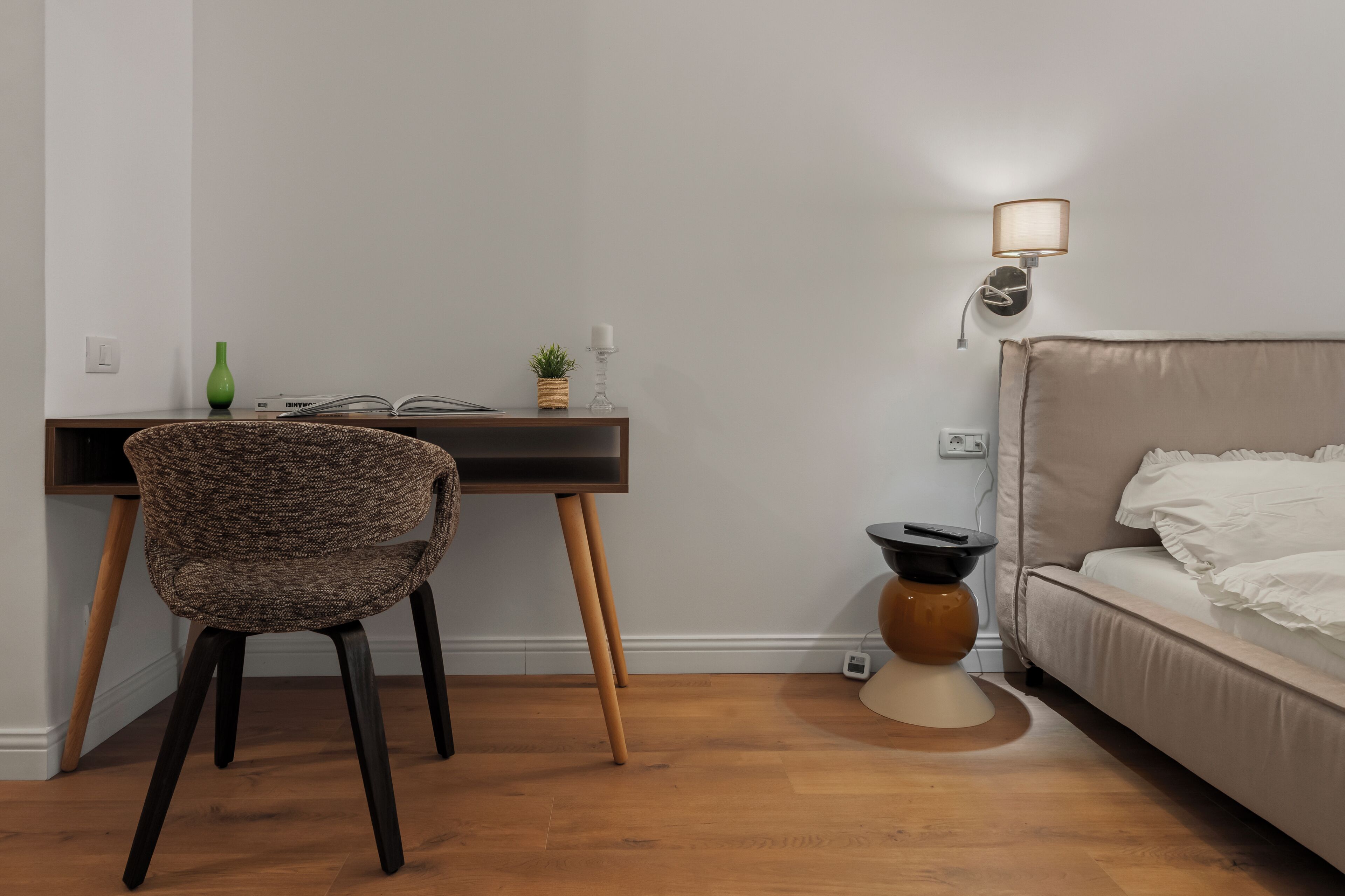 Habitació amb escriptori, cadira, tauleta de nit, làmpada i llit.