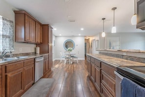 A kitchen with wooden cabinets, a central island, and pendant lighting. - Coastal Getaway: Near FIT, Downtown & Beach (Melbourne)