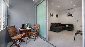 A modern living space with a dining area, a sofa, and a sliding glass door leading to an outdoor area. - Cantinho da Lurdes in Cabanas de Tavira (Tavira)