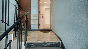A staircase leading to a room with a door, a fire extinguisher, and a doormat. - Cantinho da Lurdes in Cabanas de Tavira (Tavira)