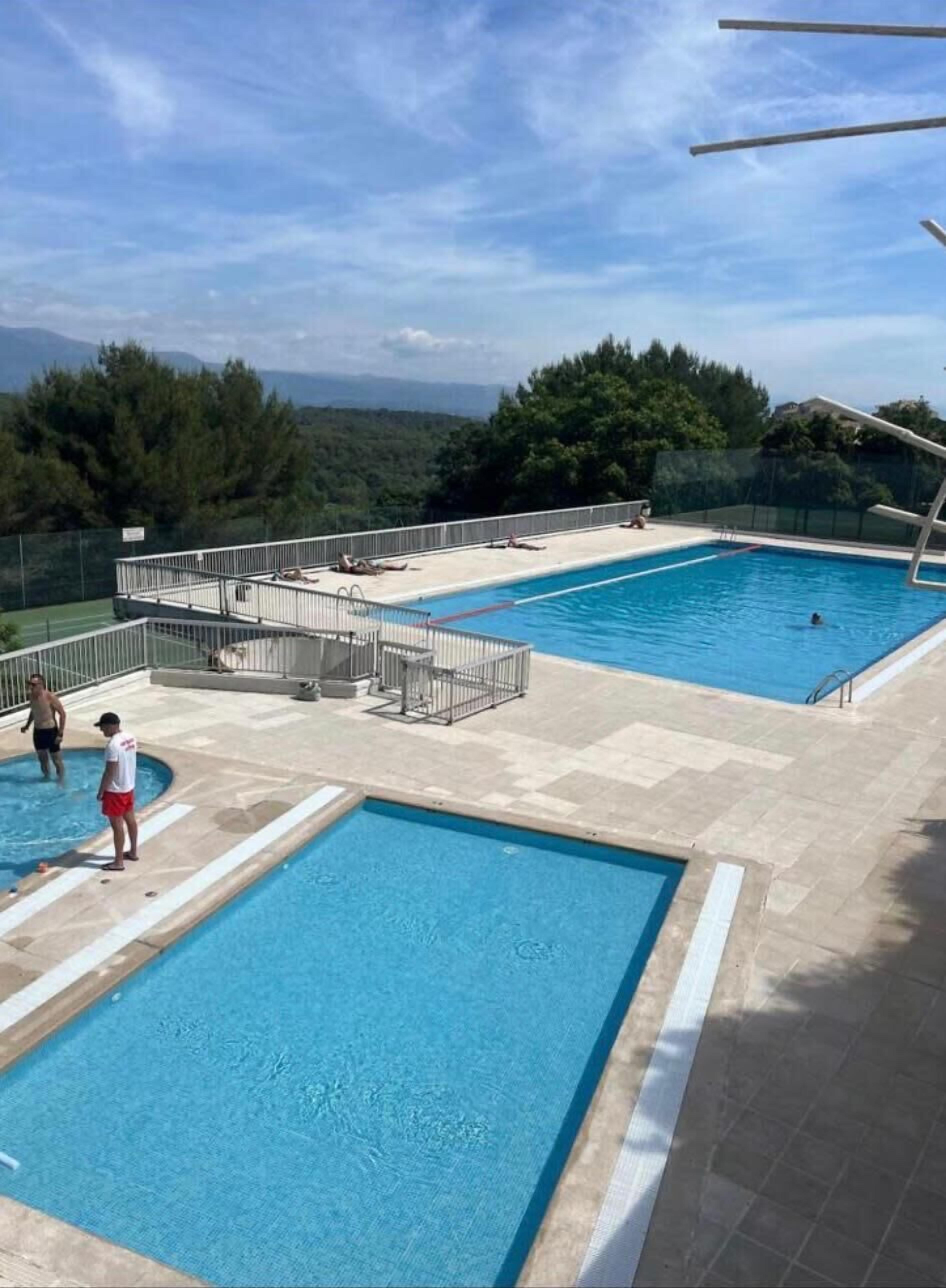 Una piscina con vistas a las montañas, un área de terraza cercada y un puesto de salvavidas.