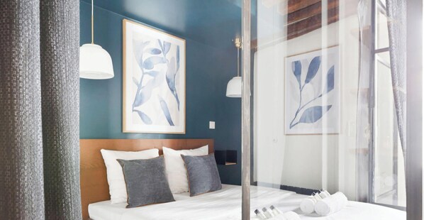 A bedroom with a bed, pillows, a headboard, and artwork on the wall. - Loft de charme avec verriere & poutre authentiques (Paris)