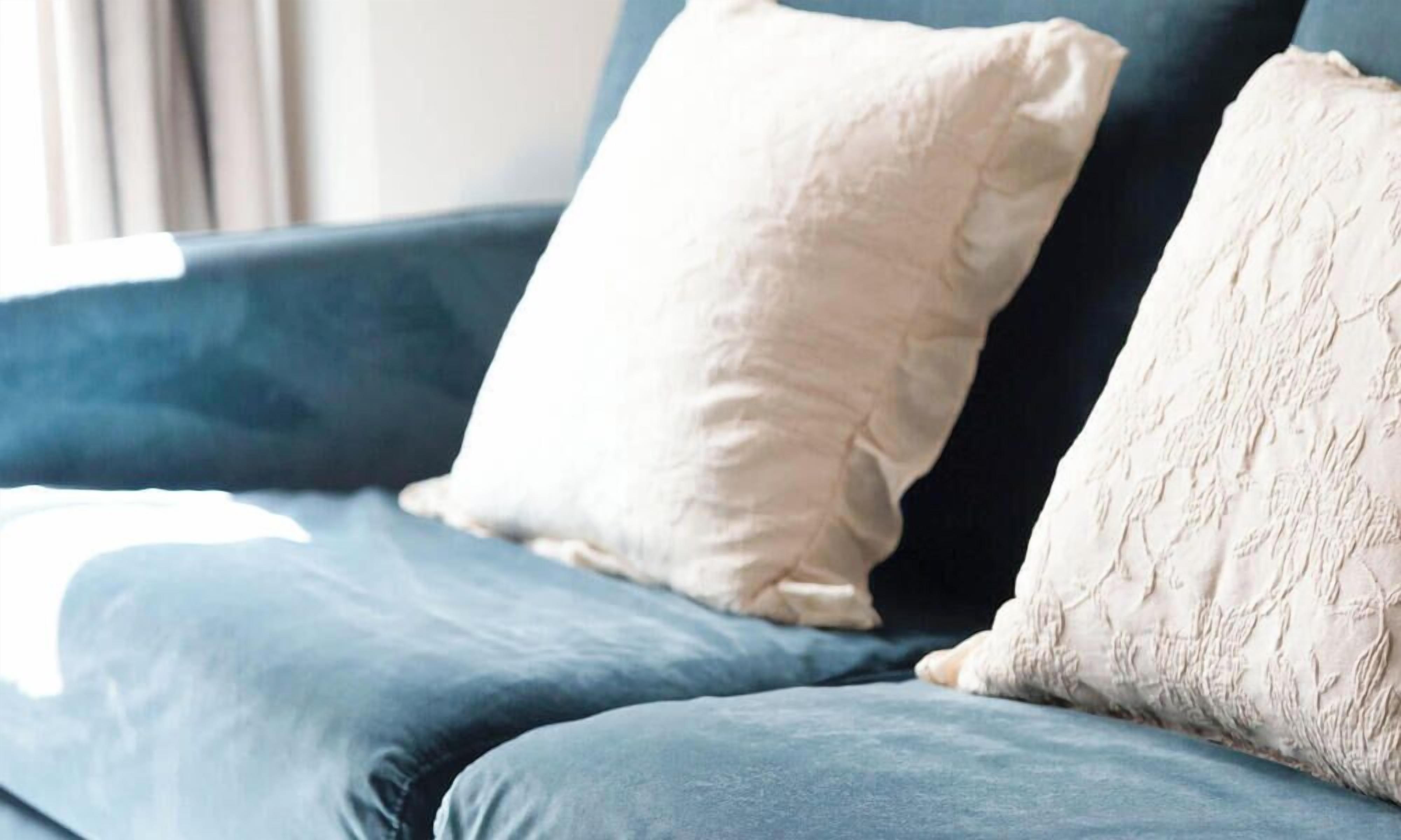 Un canapé bleu avec deux coussins, dont un uni et l’autre avec un motif texturé.