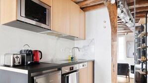 A modern kitchen with stainless steel appliances, wooden cabinets, and a marble backsplash. - Loft de charme avec verriere & poutre authentiques (Paris)