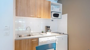 Una cucina compatta con mobili in legno, un forno a microonde, una macchina da caffè e una lavastoviglie.