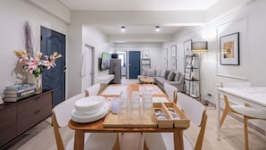 A modern dining area with a wooden table, white chairs, and a vase of flowers. - Arun Sa Wad House Lad phrao 6 Guests (Bangkok)