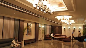 Eine Hotelhalle mit einer Kandelaber, einer Sitzecke und einer Rezeption.