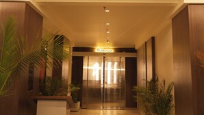 Eine Hotelhalle mit einem Chandelier, einem Schild mit der Aufschrift 'Restaurant' und Blumentöpfen.