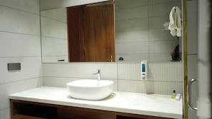 A bathroom with a white sink, a wooden cabinet, and a mirror. - Royal palm hotel and resort (Pantran)