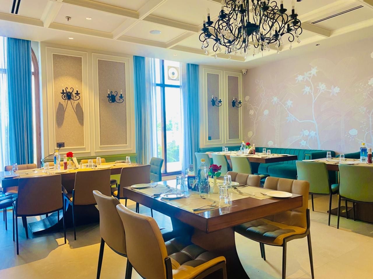 A restaurant with multiple dining tables, chairs, and a chandelier.