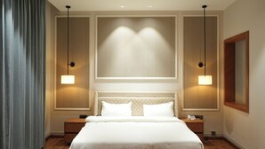 Ein Hotelzimmer mit einem großen Bett, zwei Nachttischen, einem an der Wand befestigten Telefon und zwei Pendelleuchten.