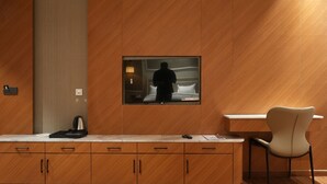 A hotel room with a wooden cabinet, a flat-screen TV mounted on the wall, a desk, and a chair. - Royal palm hotel and resort (Pantran)